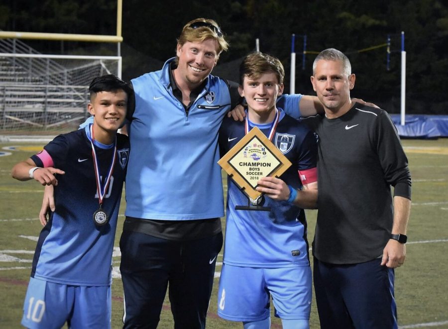 Left to Right: Midfielder Jarvin Ramirez, Assistant Coach Josh McGlamery, Defense Ethan Rose, and Head Coach Bryan Wallace celebrate their region win by holding up the teams 6-AAAAAA Champs plaque. 

