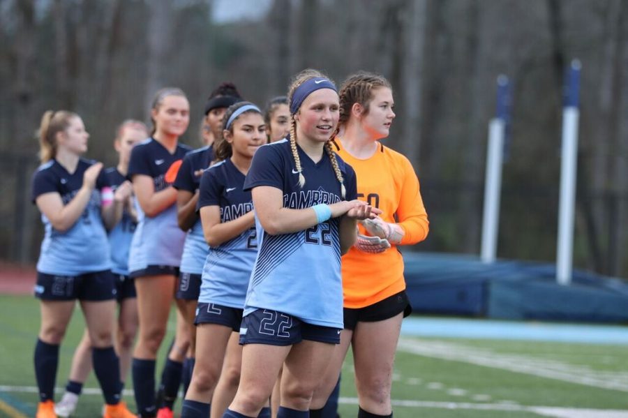 Varsity girls soccer team stands ready on the field before a game.