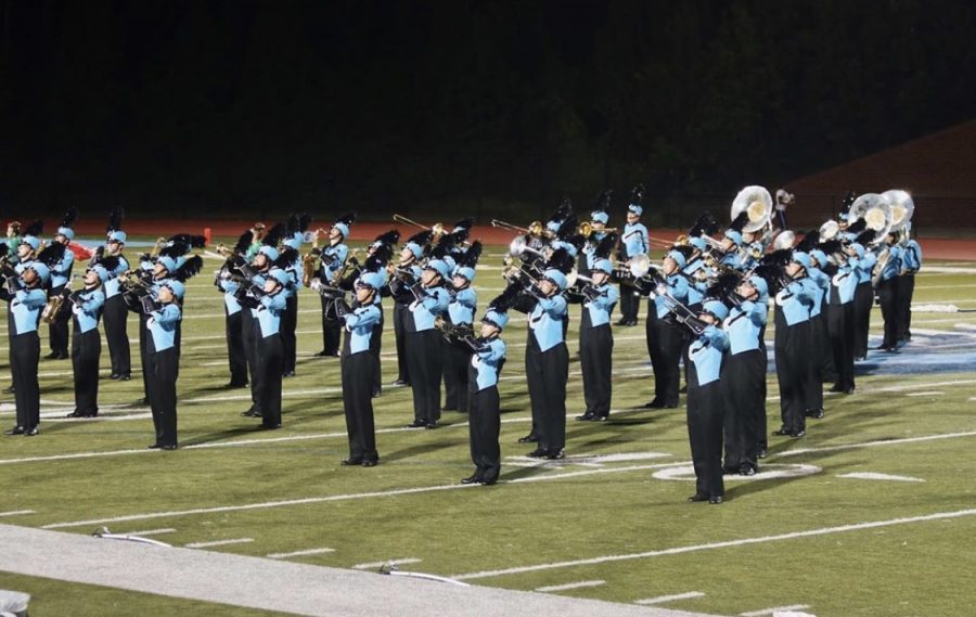 The school marching band rehearsing their set on the field at practice.