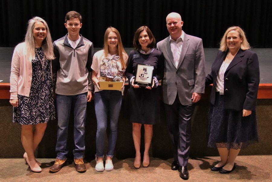 Faculty Member of the Year, Lee Leathers, holding her award and standing with her family. 