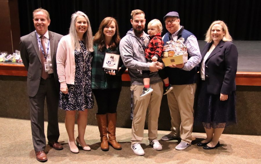 Teacher of the Year, Hal Funderburk, and his family holding his award and his baby. 