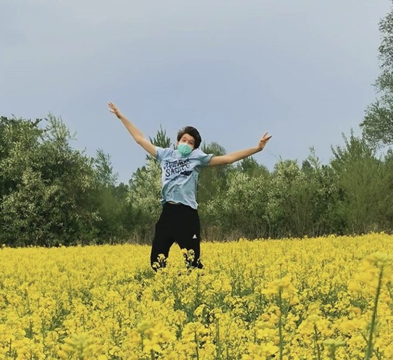 Mihael Kralj jumping for joy in a Croatian field with his COVID-19 mask. 