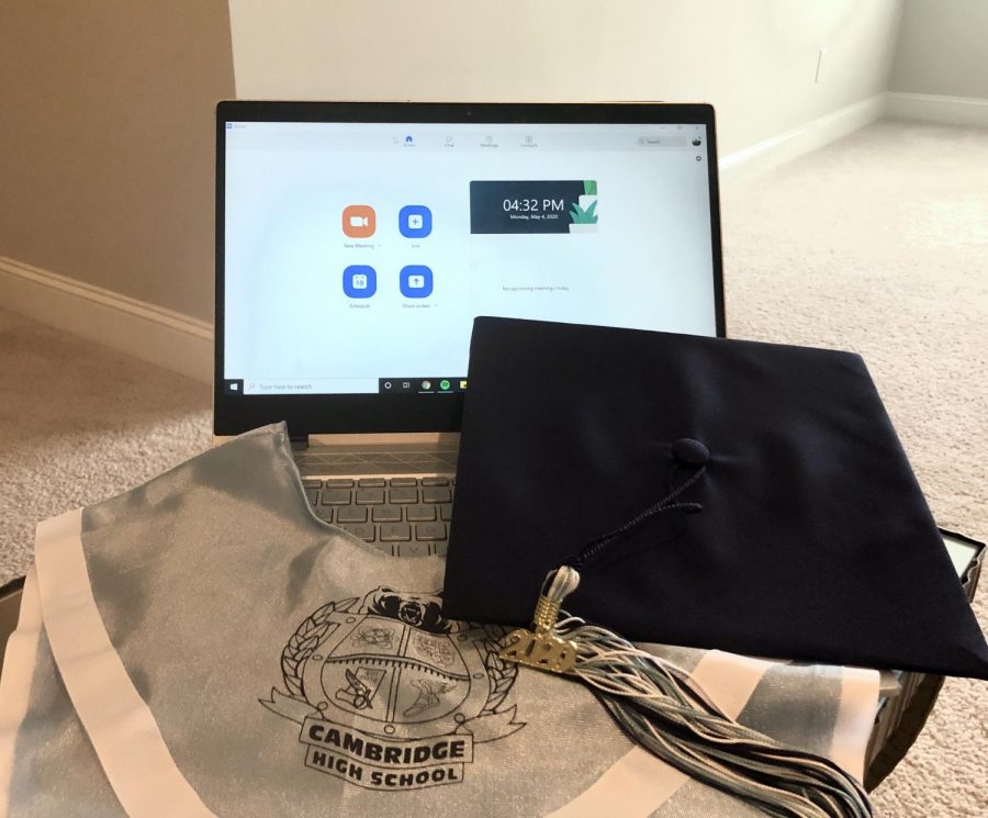 A graduation cap and Cambridge stole in front of a computer displaying the home screen for Zoom, a popular app for group video calls.