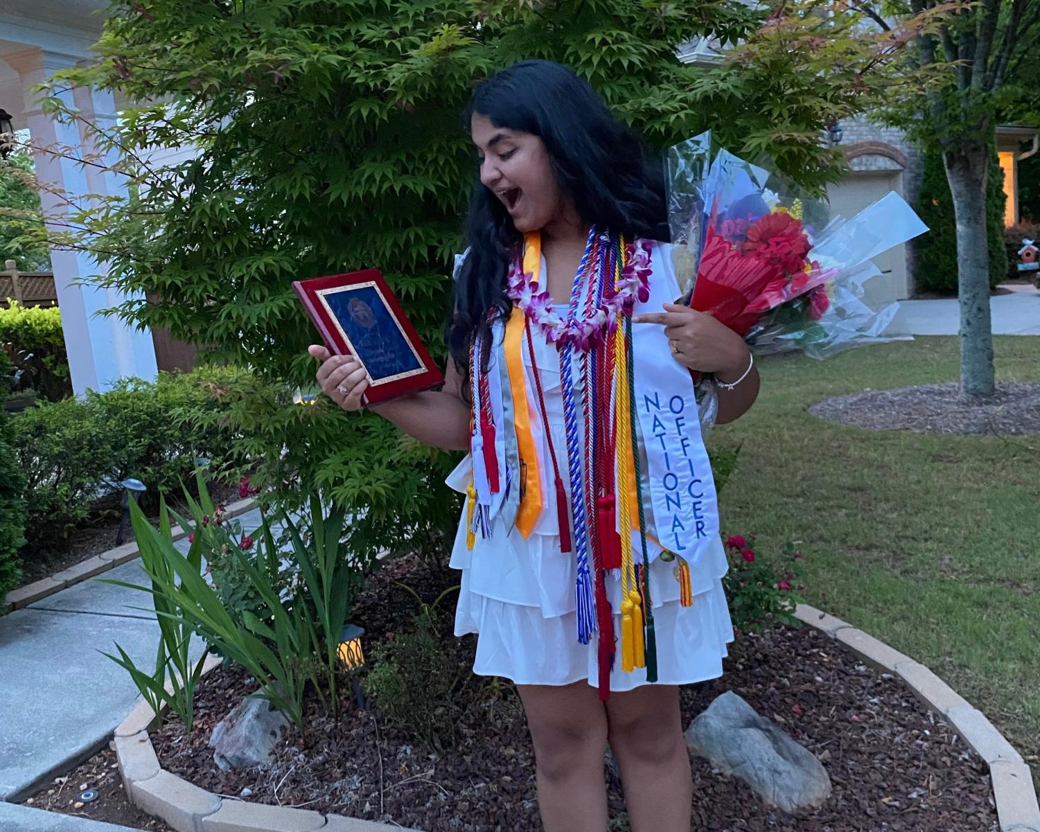 Sharma after her graduation ceremony, decked out in cords and holding her Principals Award.