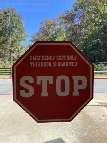 Stop sign sticker placed on exit doors warning students of alarms.