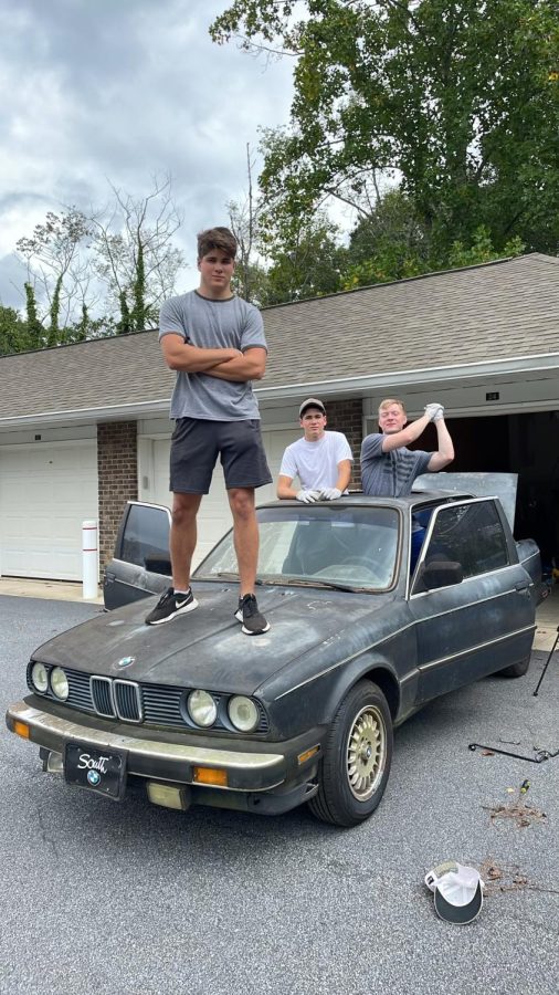 Chris Giannini, Zach Giannini, and Kyle Vipperman celebrate the purchase of their new car before they start stripping it. 